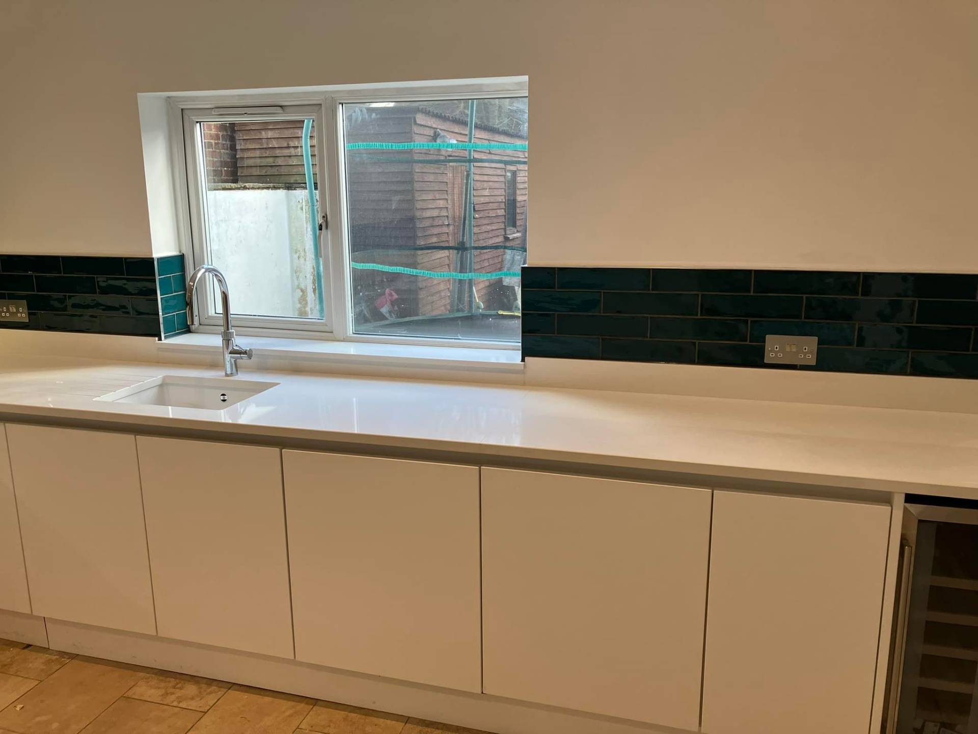 White kitchen worktop with teal splashback tiles
