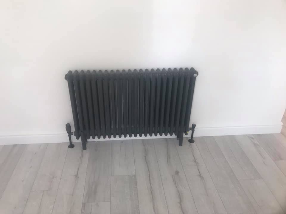 Anthracite column radiator on grey laminate flooring